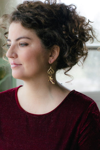 curly hair pinned up with girl wearing cranberry velvet shirt with long gold purple and pearl statement earrings