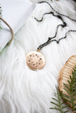 vintage gold locket surrounded by greenery on white fur background flat lay handmade in toronto