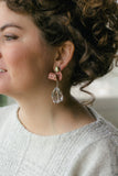 girl with curly hair in sparkle silver sweater with pink drop large earrings