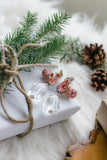 pink Japanese inspired earrings laying on white gift with twine bow and greenery