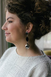 girl with curly brown hair with long black and silver vintage earrings with silver sparkly sweater